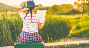 a person in a hat and plaid skirt sitting on top of a suitcase looking at a map