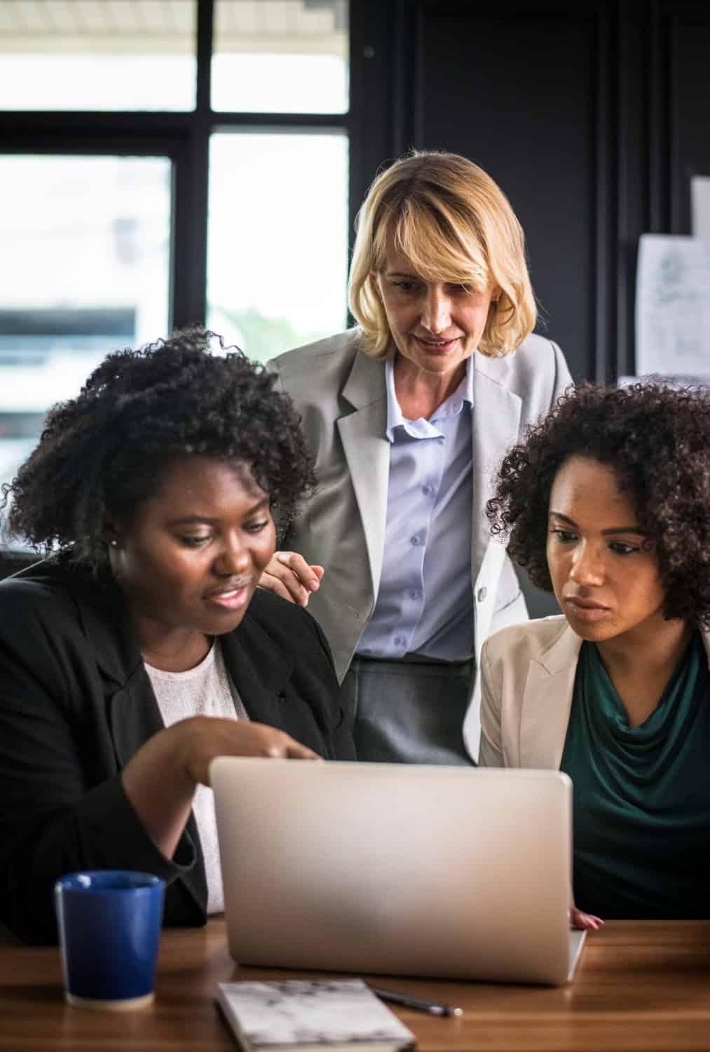 Women collaborating on a laptop in a professional office setting.